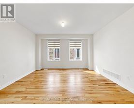 A spacious room with wooden floors and white walls.