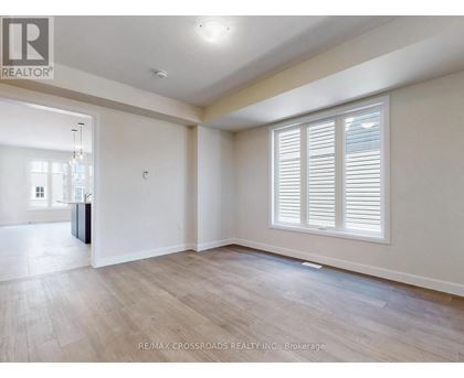 A spacious room with wooden flooring and white walls.
