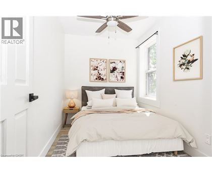 A bedroom with a bed, a ceiling fan, and two framed pictures on the wall.
