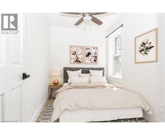 A bedroom with a bed, a ceiling fan, and two framed pictures on the wall.