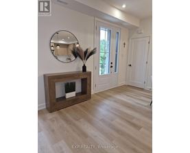 A realtor photo of a room with a wooden fireplace and a round mirror on the wall.