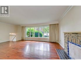 A spacious room with wooden flooring and a large window with curtains.