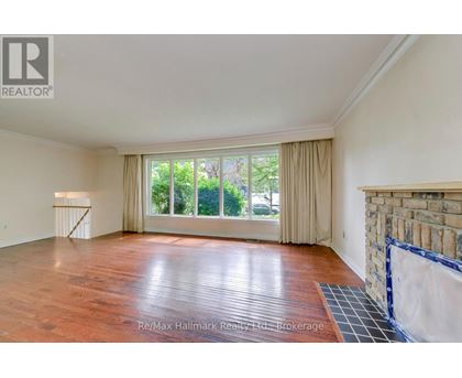 A spacious room with wooden flooring and a large window with curtains.