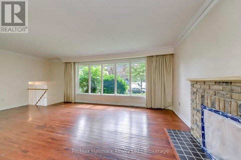A spacious room with wooden flooring and a large window with curtains.