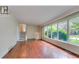 A room with wooden floors and a staircase leading to another room.