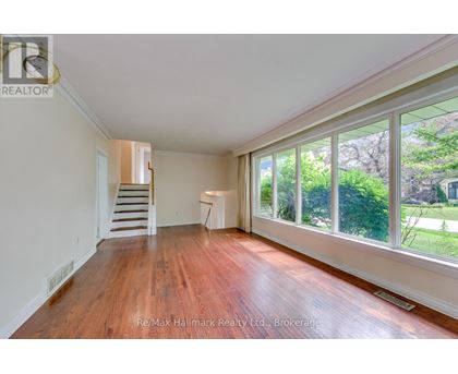 A room with wooden floors and a staircase leading to another room.