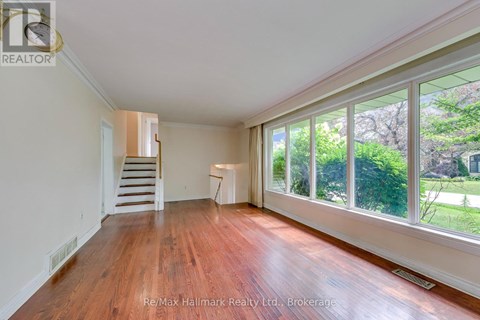 A room with wooden floors and a staircase leading to another room.