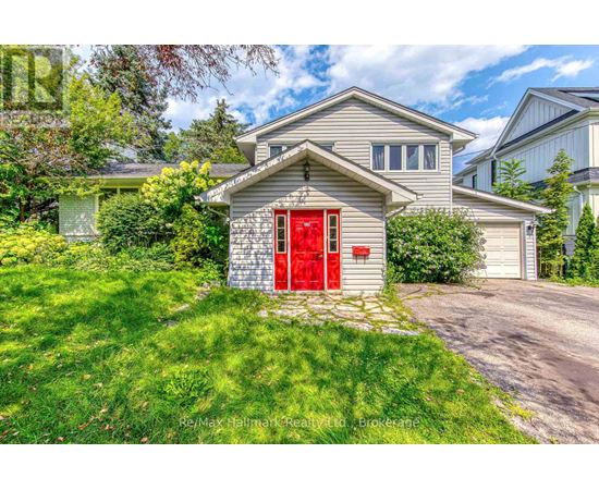 A house with a red door is surrounded by greenery.