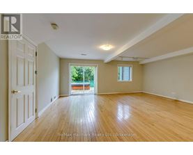 A spacious room with wooden floors and a door leading to a balcony.
