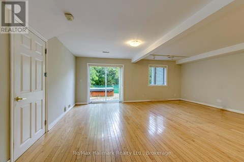 A spacious room with wooden floors and a door leading to a balcony.