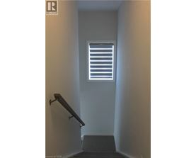 A stairway leading to a window with blinds.