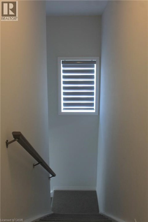 A stairway leading to a window with blinds.