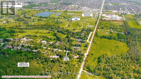 An aerial view of a property with a lake and a road passing through it.