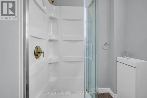 A white bathroom with a glass shower door and a white sink.