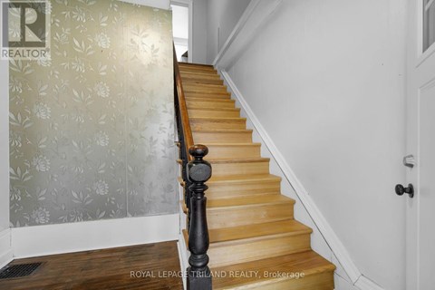 A staircase with a wooden handrail and a wallpapered wall.