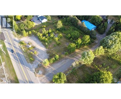 A bird's eye view of a road with a blue swimming pool and greenery.