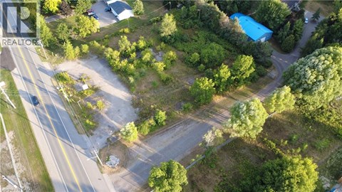A bird's eye view of a road with a blue swimming pool and greenery.