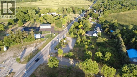 A bird's eye view of a road intersection surrounded by trees and buildings.