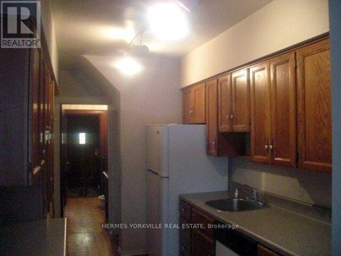 A kitchen with a refrigerator, cabinets, and a sink.