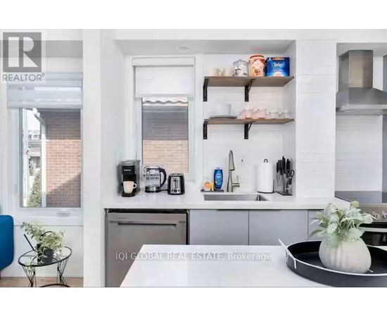 A modern kitchen with white cabinets and a black countertop.