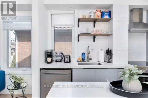 A modern kitchen with white cabinets and a black countertop.