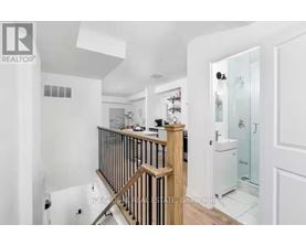 A white bathroom with a glass shower door and a wooden staircase.