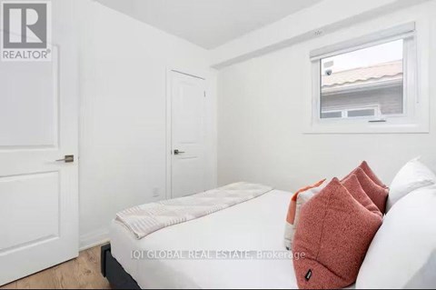 A bedroom with a bed, a window, and a door.