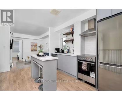 A modern kitchen with stainless steel appliances and a wooden floor.