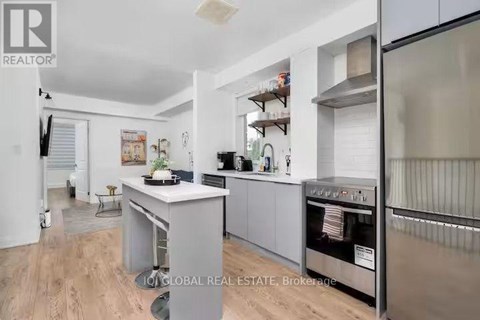 A modern kitchen with stainless steel appliances and a wooden floor.