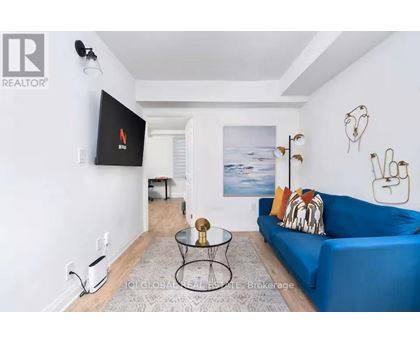 A living room with a blue couch and a flat screen TV mounted on the wall.