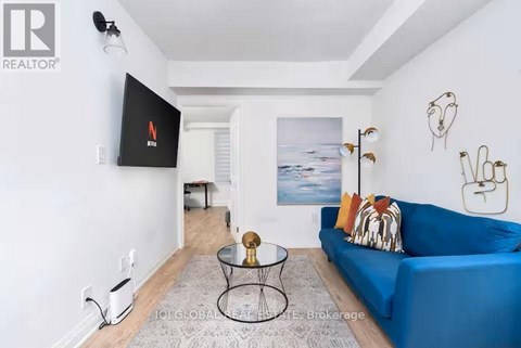 A living room with a blue couch and a flat screen TV mounted on the wall.