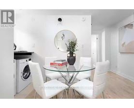 A modern dining room with a glass table and white chairs.
