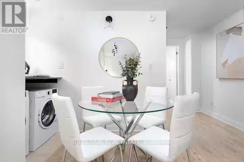 A modern dining room with a glass table and white chairs.