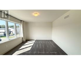 A spacious room with a carpeted floor and large windows.