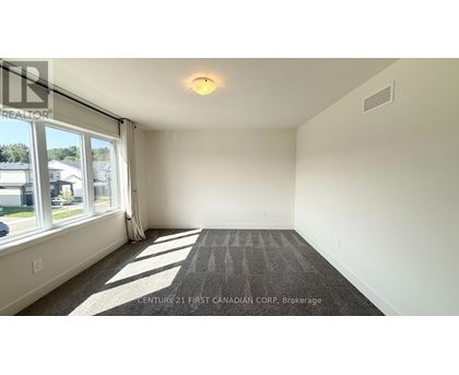 A spacious room with a carpeted floor and large windows.