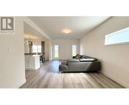 A spacious living room with a large black sofa and wooden flooring.