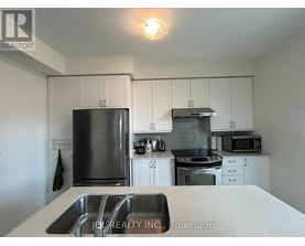 A kitchen with white cabinets and a stainless steel refrigerator.