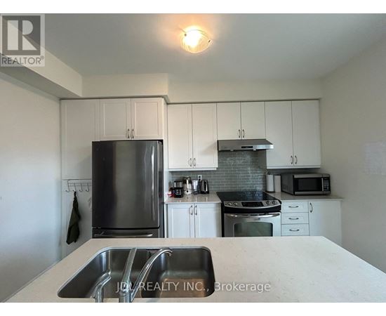A kitchen with white cabinets and a stainless steel refrigerator.