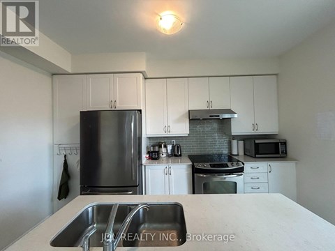 A kitchen with white cabinets and a stainless steel refrigerator.