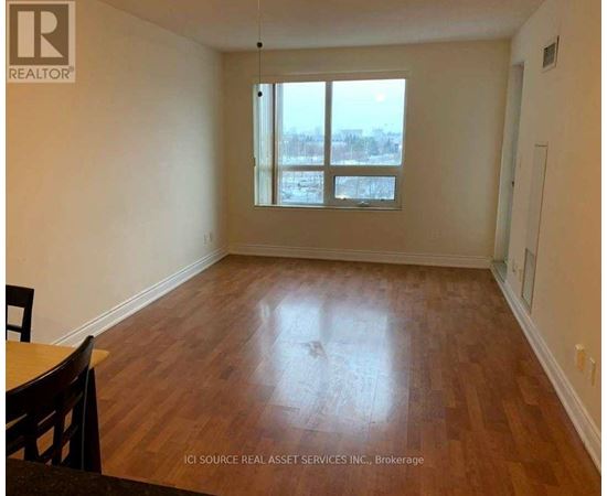 A room with wooden flooring and a large window.