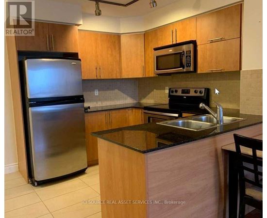 A kitchen with wooden cabinets and a stainless steel refrigerator.