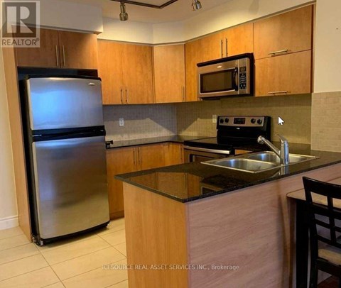 A kitchen with wooden cabinets and a stainless steel refrigerator.