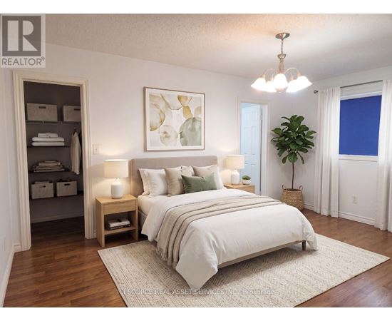 A bedroom with a large bed, a chandelier, and a painting on the wall.