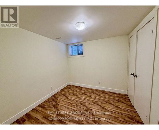 A room with wooden flooring and a window with blinds.