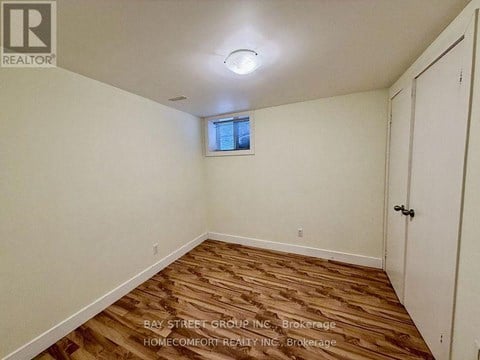 A room with wooden flooring and a window with blinds.