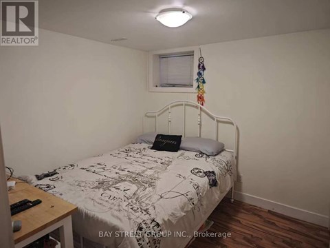 A bedroom with a bed, a desk, and a window.