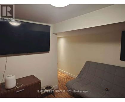 A living room with a grey couch and a flat screen TV mounted on the wall.