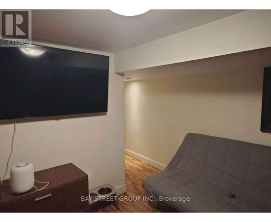 A living room with a grey couch and a flat screen TV mounted on the wall.