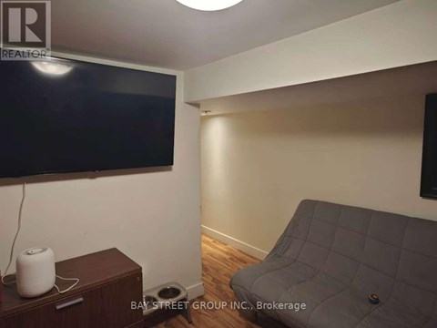 A living room with a grey couch and a flat screen TV mounted on the wall.
