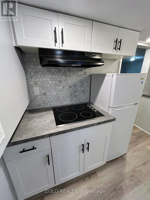 A kitchen with white cabinets and a black stove top.